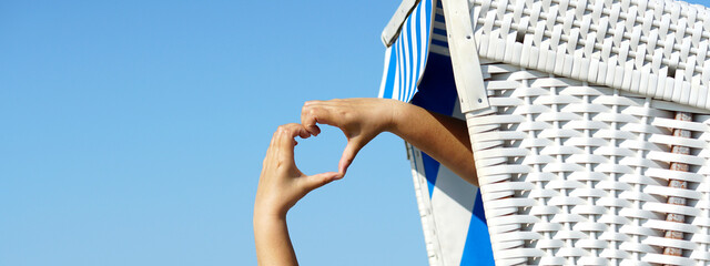 Herz mit den Händen formen im Strandkorb