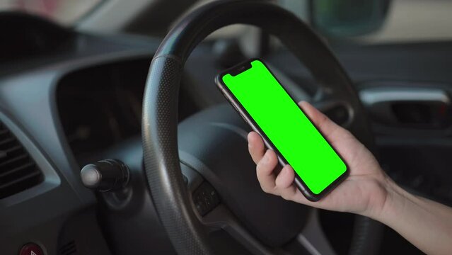 Hand using smartphone green screen at car, phone in hand on car