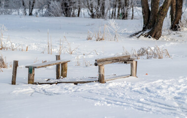 Old broken wooden bridges covered with snow on the river in a winter landscape.
