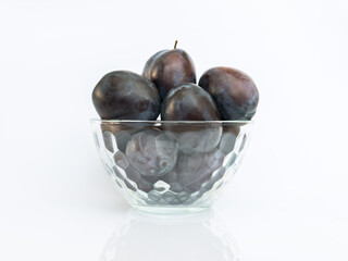 Plums in a glass bowl isolated on white background