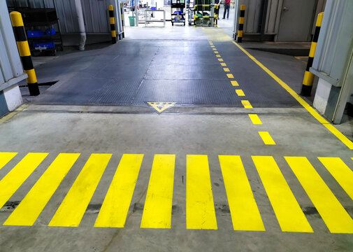 Industrial building corridor painted yellow between parallel yellow lines on abstract cement background. Sidewalk Negotiation Safety Concept