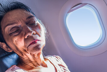 Portrait of an old woman sitting by the window in a flying plane