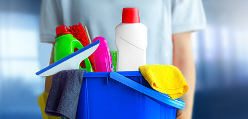 Housekeeper with bucket of cleaning products on blurred office background. Clean service concept.