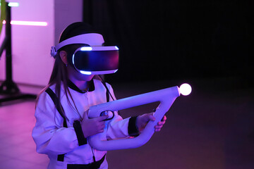 Girl playing in computer games center in glasses with gun in hands, virtual reality