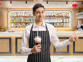Waiter smiling and holding a takeaway coffee at a bar