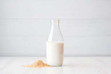 oat milk in transparent bottle, white surface
