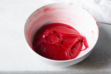 Red velvet batter in a white mixing bowl, process of making red velvet madeleines, thick red cake batter in a white ceramic bowl