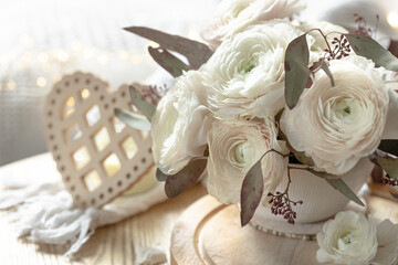 Bouquet of white ranunculus flowers on a blurred background with a heart.
