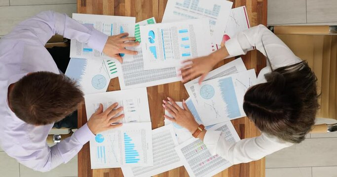 Business woman and man nervously looking for document top view