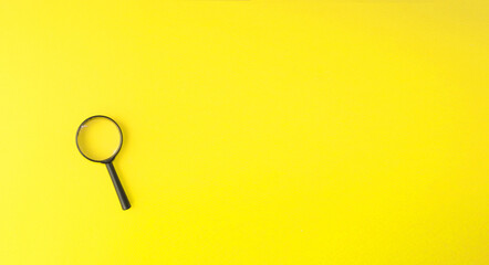 Magnifying glass, magnifying glass in a black frame on a yellow background.  Concept research, objects magnification.  Flat top view.  Space for copying text.