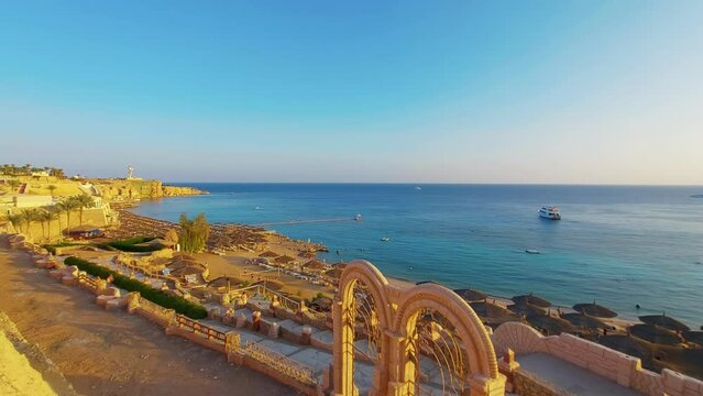 Sea harbor at sunset, Ras Um Sid. Shark's Bay Beach. Resort town of Egypt, Sharm El Sheikh. Vacation rest holiday concept. Beach umbrellas along the shore. Sightseeing attraction