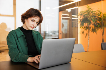 Gen Z business woman working on laptop. Flexible office for startups. Creative female looking into the computer at coworking space. Small online business owner