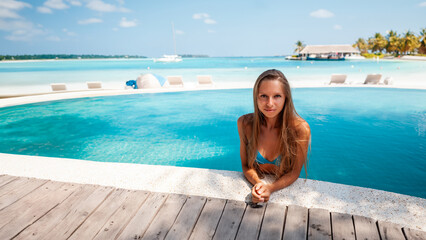 Travel vacation - Beautiful young pretty blonde girl back in bikini on her perfect sport sexy body relax in pool near paradise beach at tropical caribbean maldives beach at sunny day in hotel