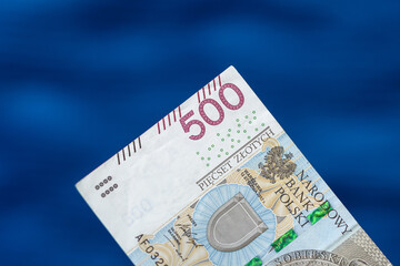 Izolowany polski banknot papierowy 500 złotych na niebieskim rozmytym tle