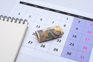 Polskie pieniądze leżą na kartce z kalendarza , planować wydatki  - obrazy, fototapety, plakaty