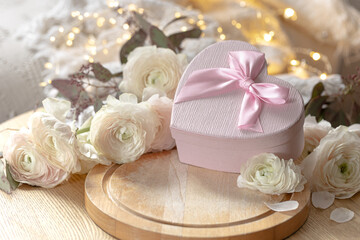 Composition with a pink heart-shaped gift box and flowers.