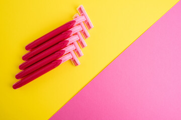 Pink women's razors isolated on yellow and pink background. Pink women's disposable razors. Skin and body care concept. Depilation. Place for text