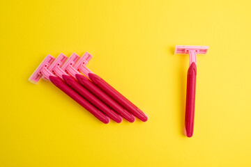 Pink women's razors isolated on yellow and pink background. Pink women's disposable razors. Skin and body care concept. Depilation. Place for text