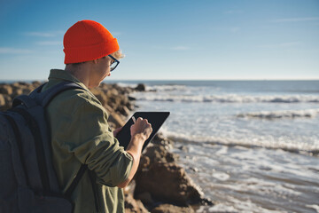 Young marine biologist studying marine fauna with an electronic tablet on the seashore. Control of the environment. - obrazy, fototapety, plakaty