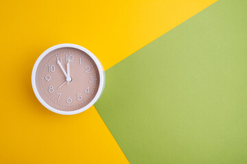 White alarm clock on a colored background. Fashionable minimalist style. Time, business and technology concept. Flat composition. View from above