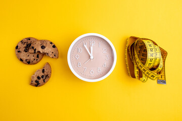 Cookies with chocolate chips and tape measure, on a yellow background. Diet and proper nutrition...