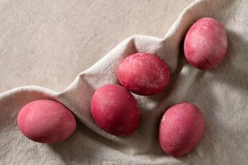 Pink colored Easter eggs on beige linen tablecloth background, lifestyle, soft natural sun light shadows