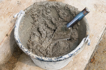 Mix cement sand and stones with hoe leak inside big bucket on floor background - 720101502