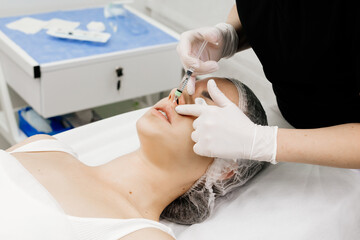 Close-up, woman's lips. A cosmetologist injects hyaluronic acid into a woman's lips using a...