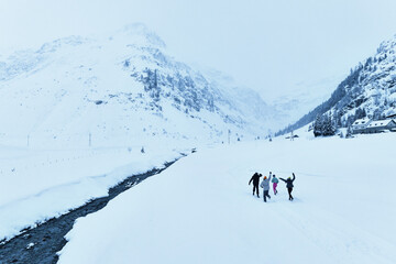 Eine Gruppe von modernen und jungen Freunden, die durch die Berge in einer Winterlandschaft bedeckt...