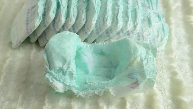 A small feather falls into a baby diaper on a white background. The concept of lightness and tenderness. Comfort and convenience for children, close-up