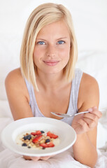 Obraz na płótnie Canvas Breakfast, portrait and woman in a bed with muesli, meal or berries for balance, wellness or gut health at home. Fruit, eating or female person face in bedroom for diet, nutrition or superfoods snack