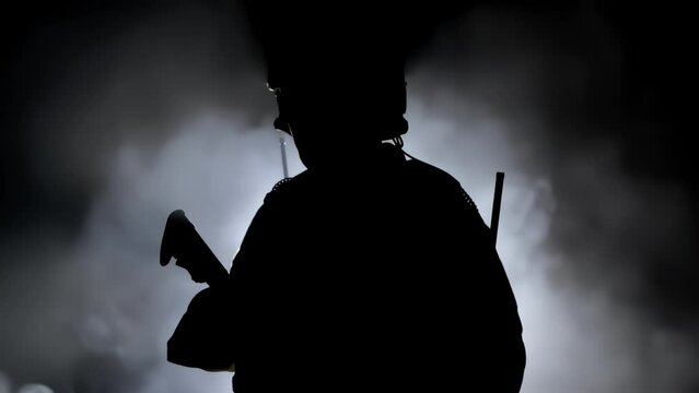 Military soldier in army camouflage stands, silhouette warrior with weapon assault rifle carbine. Shadow of mercenary in uniform and helmet. War concept. Private military company. Fog smoke background