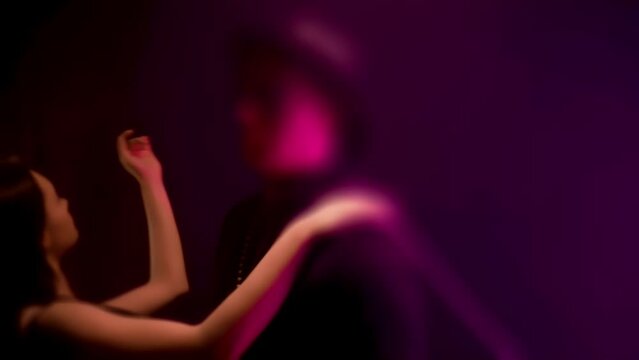 Sexy brunette go-go girl doing a private dance next to a man in a black suit and hat, hot erotic striptease in nightclub. BDSM fetish concept. Intimate adult games. Tilt-shift lens shot