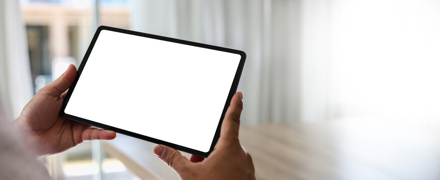 A businessman holds a mockup. iPad digital tablet with blank screen Mockup replaces your design mockup in the office.