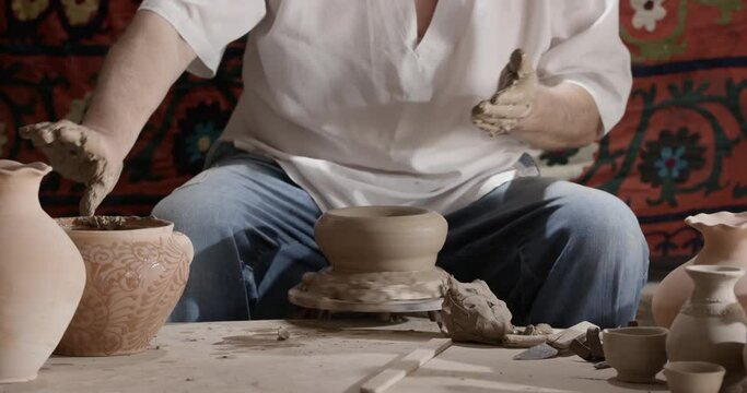 Hands of a master potter working on a potter's wheel in the manufacture of dishes