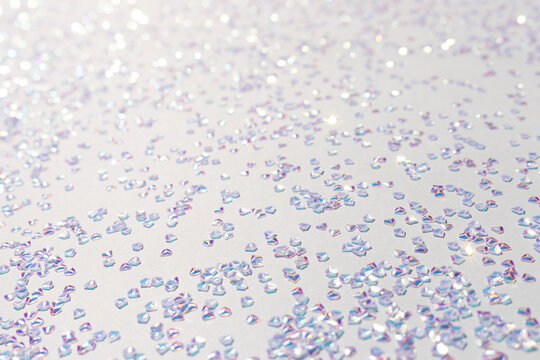 Glowing silver crystal confetti on a blue background. Selective focus.