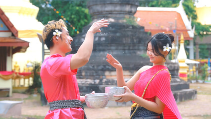 Couple wearing traditional Thai clothes happy playing songkan During the Songkran festival of...
