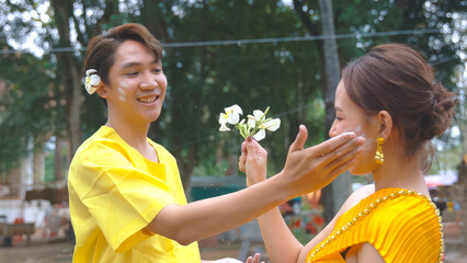 A young man politely applies powder to a young woman. During the Thai Songkran festival