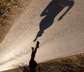 Shadow cast on a paved road of a fit young female runner running with a perfect style and her hair...