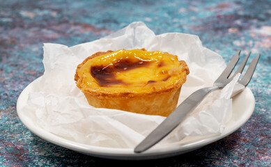 Plate with one Portuguese Pastel de Nata quiche. Pastel de Belem is a monastic and cult pastry in the form of cups with a burnt top and a crispy puff pastry crust. Sweet dessert with egg cream.