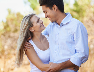 Obraz premium Couple, face and happy or hug with travel in forest, nature or outdoor for holiday, vacation or trip. Romance, man and woman with embrace or smile for relationship, summer date or honeymoon with love