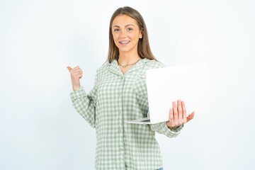 young beautiful woman wearing green plaid pyjama,  directing empty space  hold laptop