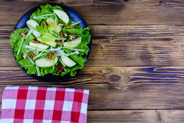 Plate with waldorf salad on a wooden table. Top view