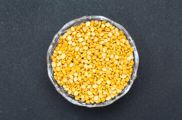 Split chickpeas or chana dal in a glass bowl on black background top view 