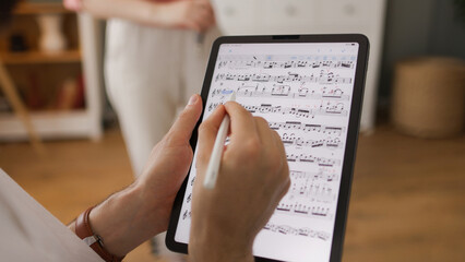Male music teacher giving private violin lessons to a teenage girl using digital tablet