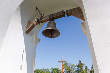 Church bell in arched belfry on yard of Christian church