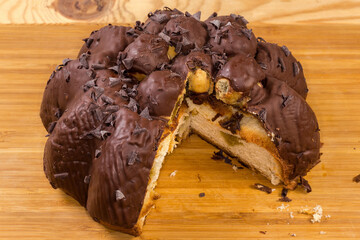 Partly cut chocolate panettone with profiteroles on the cutting board