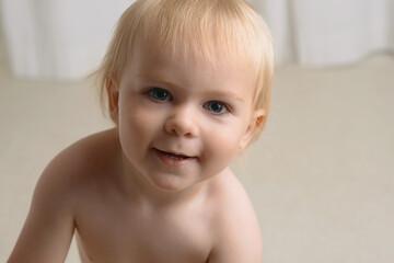 Happy baby, portrait and blonde boy in growth, youth or development in living room at home. Closeup...