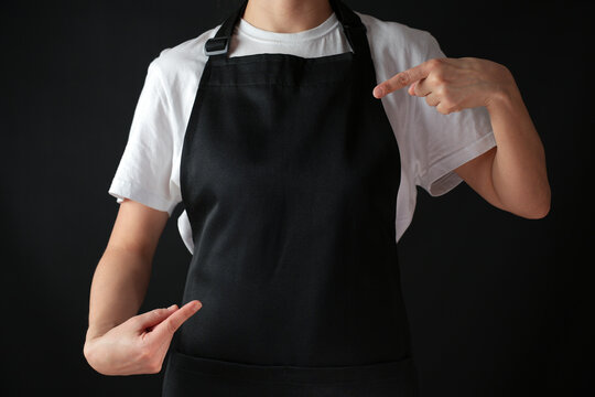 Woman chef pointing on black apron, close-up
