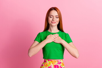 Portrait of thankful satisfied girl with redhead hair wear stylish top arms on chest eyes closed...
